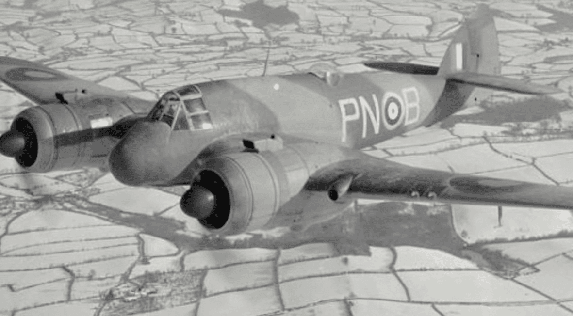 A Bristol Beaufighter bearing โPN-Bโ markings in flight above a patchwork of snowy fields.