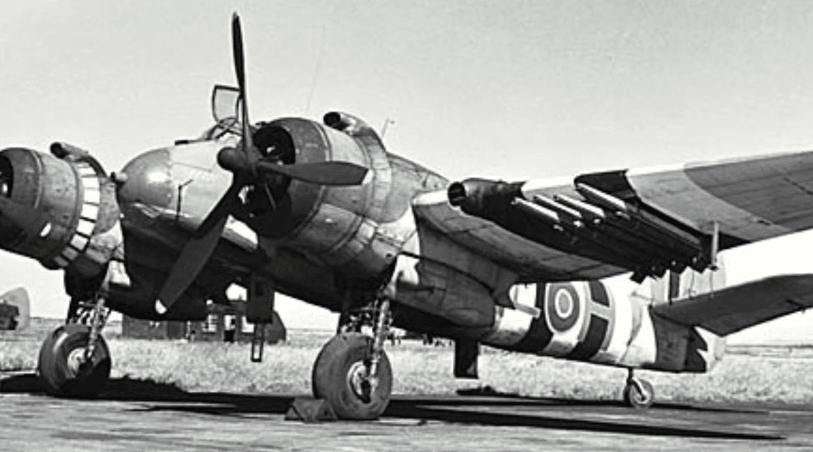 A Bristol Beaufighter equipped with rocket projectiles under its wings, parked on an airfield.
